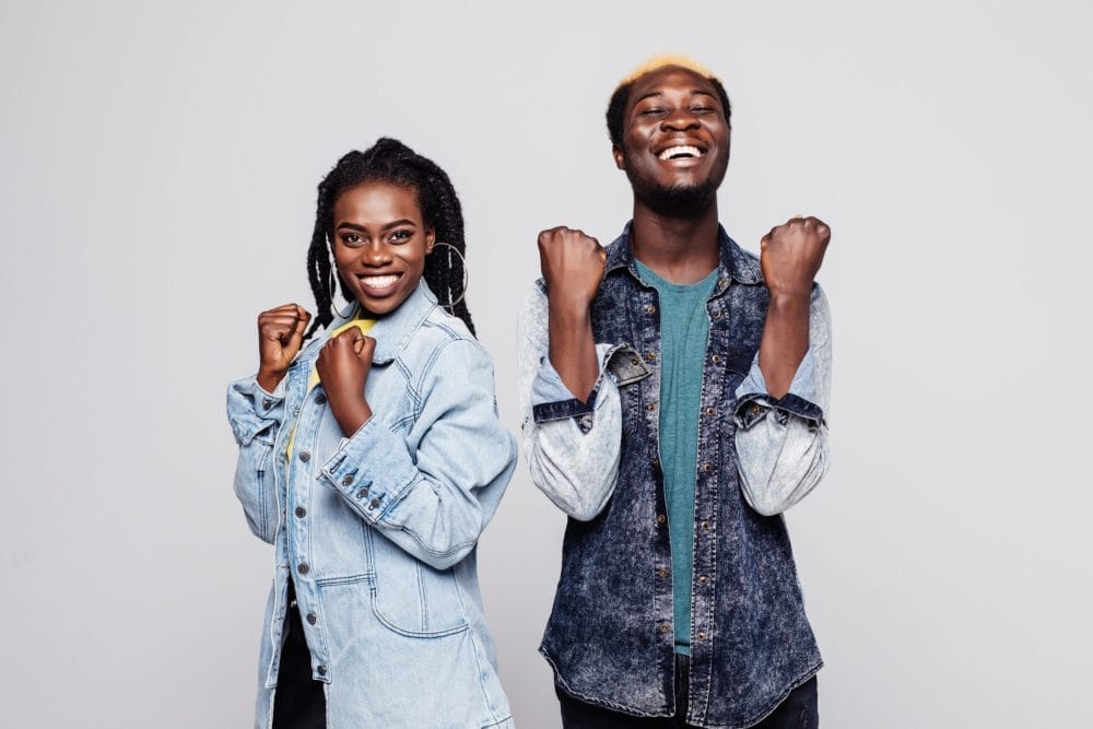 Portrait of a happy young afro american couple screaming and celebrating isolated over white background